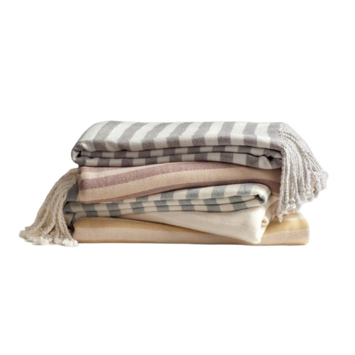 A collection of bamboo viscose throws in various colors, featuring a striped pattern, folded and displayed on a flat surface.