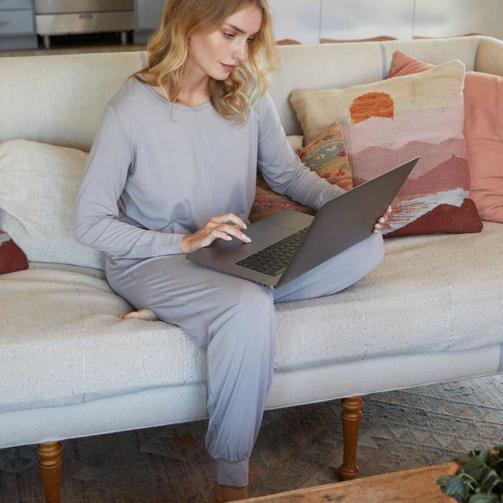 Woman sitting on a couch typing on her laptop wearing a Pure Fiber bamboo viscose 2 piece long sleeve loungewear set